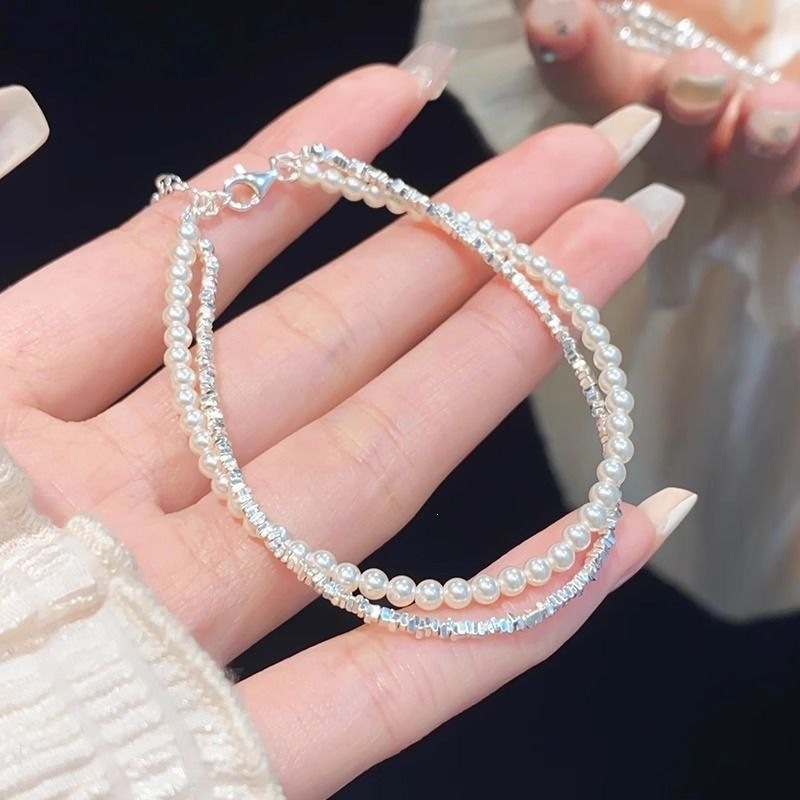 Pulseira de duas camadas com pérolas e prata na mão de uma mulher